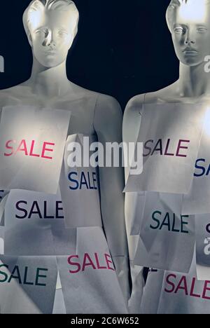 Retail sale sign attached to two mannequins  in  a storefront window Stock Photo