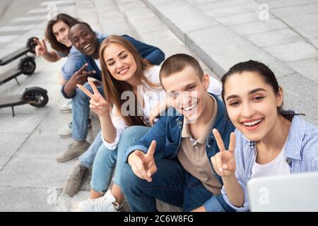 Five teens using motorized kick scooters, taking selfies Stock Photo