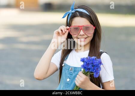 Wishing happy anniversary. Happy kid hold flowers outdoors. Fashion look of little girl. Cornflower bouquet for celebrating anniversary. Anniversary celebration. Birthday anniversary. Summer holidays. Stock Photo