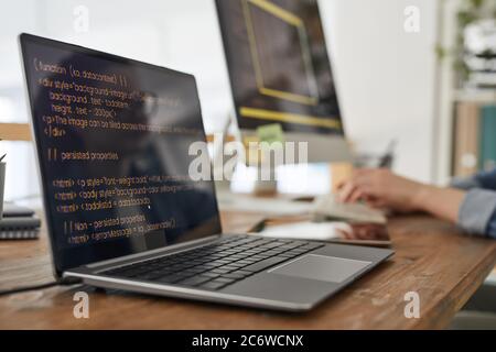 Close up of two computers with programming code on screen in minimal home office interior with hands typing in background, copy space Stock Photo