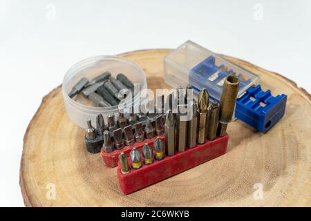 Screwdriver bits and tips lie on a round cut of wood in a carpentry workshop Stock Photo