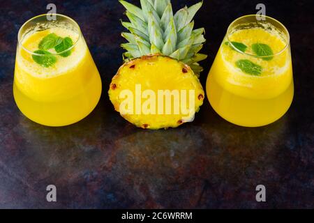 Pineapple juice on a dark background. Juice for detox in the glass. Pineapple smoothie with fresh pineapple. Summer drink on a black background. Top v Stock Photo