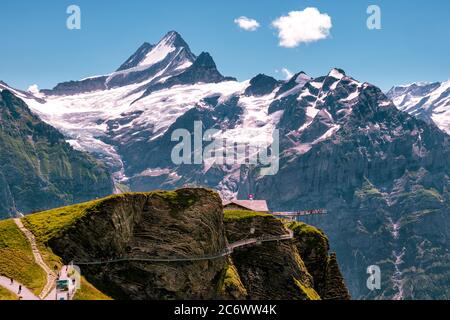 Grindelwald First, Bernese Oberland, Switzerland - July 30 2019 : Tourists walk on the First Cliff Walk enjoying a breathtaking view on some high snow Stock Photo