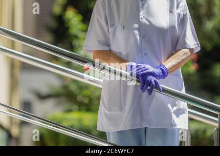 Details with the hands of a woman medic leaning patiently on a metal rail. Stock Photo