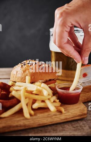 Different types of fastfood and snacks and glass of beer on table. Unhealthy and junk food. Stock Photo