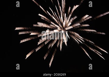 close up of a single burst of a crysanthemum rocket fireworks explosion glowing against the night sky from a new york city rooftop Stock Photo