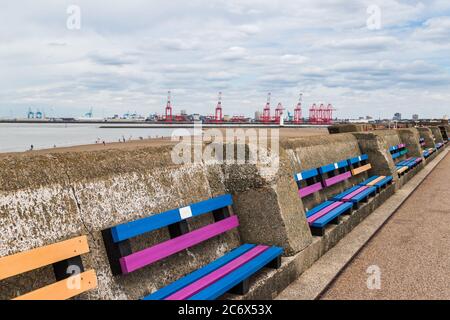 Colourful benches on Wallasey beach promenade fade out of the frame on the Wirral near Liverpool in July 2020. Stock Photo