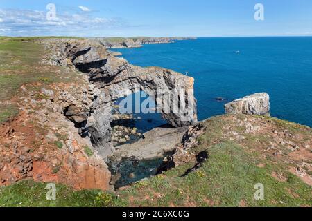 Man standing on arch of Green bridge of Wales nr Castlemartin, Pembrokeshire Wales UK Stock Photo