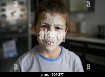 Offended unhappy boy with face covered with flour in kitchen Stock Photo