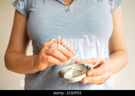 Female hands taking out from case two transparent dental aligners Stock Photo