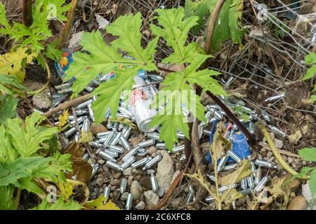Numerous discarded nitrous oxide bulbs or containers, cans, also known as laughing gas or hippy crack. Litter, littering, mess, England UK Stock Photo