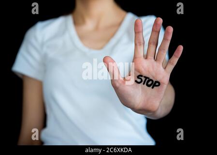 Woman holding out hand in stop gesture with word Stop written on open palm Stock Photo
