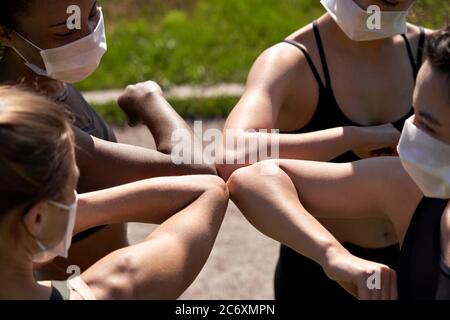 Diverse multiracial fit girls friends wear face masks give elbow bump. Stock Photo