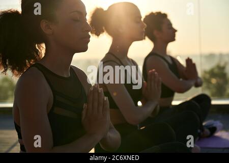 Calm serene african american woman meditating at outdoor group yoga class. Stock Photo