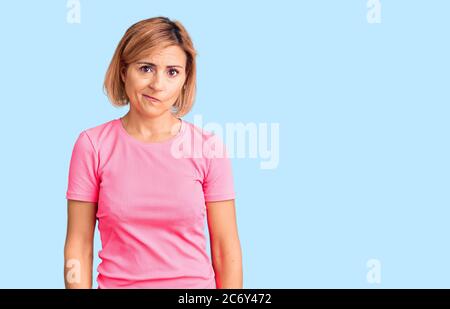 Young blonde woman wearing sportswear looking sleepy and tired, exhausted for fatigue and hangover, lazy eyes in the morning. Stock Photo