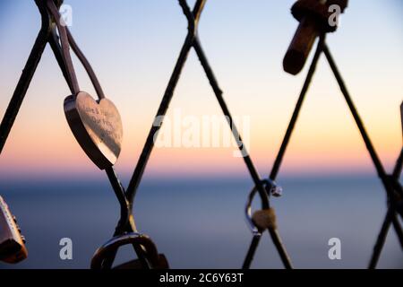 Padlock on heart shaped fence with sunset background Stock Photo