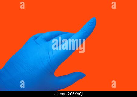 Human hand in latex blue medical glove isolated on orange with gesture. Protection concept Stock Photo