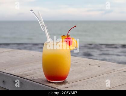 Glass of fruit punch on wood top with ocean view Stock Photo