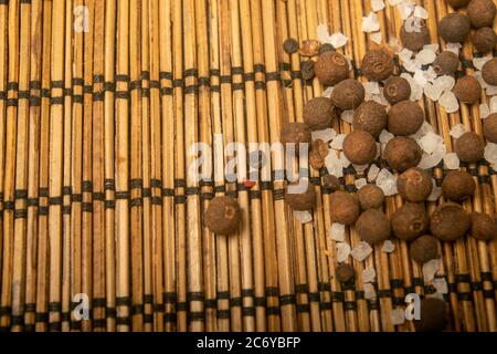 Fragrant black pepper and coarse sea salt in bulk on a reed Mat. Close up Stock Photo