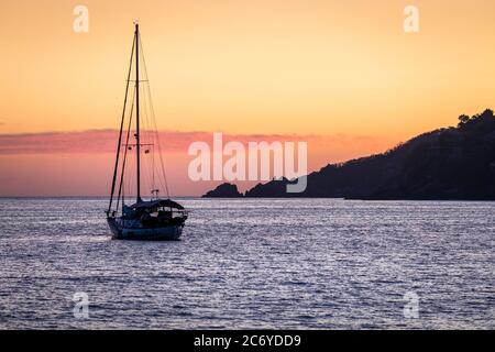 A sailboat floats in the bay of Zihuatanejo, Mexico at dusk. Stock Photo