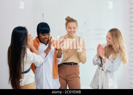 Young ladies clapping hands, good job of four diverse female working on business project, celebrate their success in office, laptop on table. white of Stock Photo