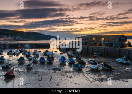 Lyme Regis, Dorset, UK.  13th July 2020.  UK Weather.  Clouds drift across the sky above The Cobb harbour at Lyme Regis in Dorset shortly before sunrise.  Picture Credit: Graham Hunt/Alamy Live News Stock Photo