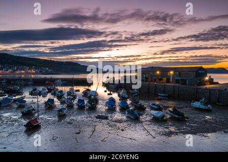 Lyme Regis, Dorset, UK.  13th July 2020.  UK Weather.  Clouds drift across the sky above The Cobb harbour at Lyme Regis in Dorset shortly before sunrise.  Picture Credit: Graham Hunt/Alamy Live News Stock Photo
