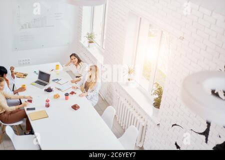 top view on business coworking process in white modern office, use laptop, papers. Creative group of people working Stock Photo