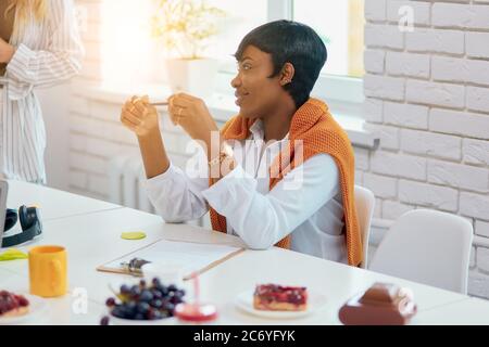 beautiful african business lady sit listening to her business partner or coach , wearing white shirt and orange blouse on shoulders, short dark hair. Stock Photo