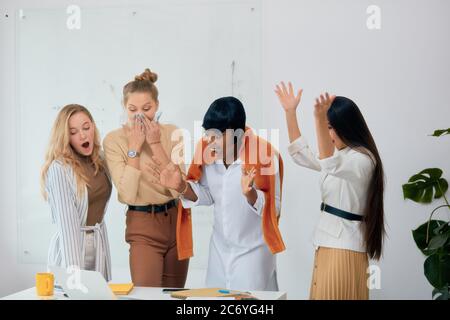 Surprised young businesswomen dressed in casual clothes stay in shock after news about their winning in business project, share success with each othe Stock Photo