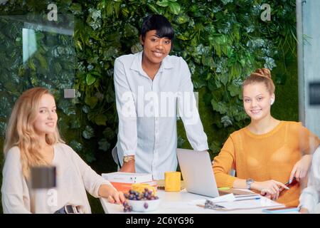 Smiling black manager coach speaking at caucasian corporate group meeting, african coach, leader talking to office workers at training teaching employ Stock Photo