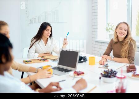 Beautiful good-looking business women coworking in office using laptop, white modern office background Stock Photo