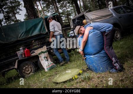 Martin, son of Juan, whants to help his father to take the couch from the trailer of the support car to his car parked by the lunch camp in the middle of the mountains of Cuenca, next night Juan will sleep at his home in Frías de Albarracín , Spain. Date: 28-06-2016. Photographer: Xabier Mikel Laburu. The transhumance walk will take Enrique Belinchon, his cousin Alejandro Belinchon, his son Aitor Belinchon and their friend Juan Ahufinger, to drive their flocks of sheep along 400Km to the Albarracín Mountains in Teruel for the summer pastures. Stock Photo