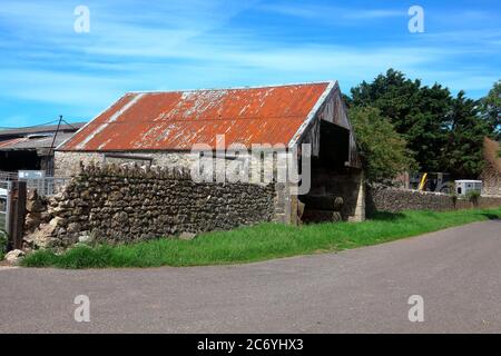 An old roadside store for very large farming tools or tractors or even a  combine harvester, with a rusty tin roof and open plan entrance. Stock Photo