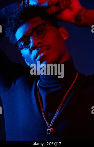 Handsome young African man with glasses and casual wear on dark blue background. Stylish and successful fashion designer or modeler. Stock Photo