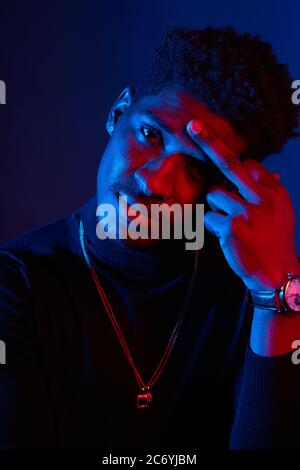 Grieved depressed sad young dark-skinned man having some problems with health or private life. Isolated studio shot of tired african man keeping hand Stock Photo