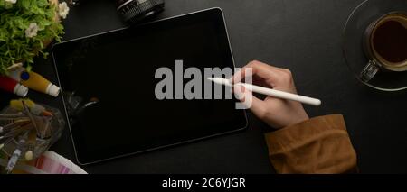Top view of female designer drawing on digital tablet with stylus pen on worktable with painting tools Stock Photo