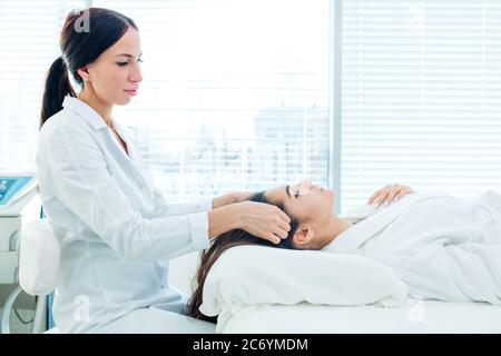 Cosmetology image of beautician doing head massage or prepare female patient to hardware cosmetology procedures. Beauty concept. Cosmetology concept. Stock Photo