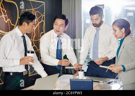 Business team gathered in meeting room to discuss reports and financial documents and trying to find the best way to overcome financial crisis Stock Photo