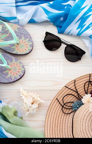 Summer holiday background with seashell, flip flops sandals, sunglasses, pareo and straw hat on wooden boards. Concept of beach and sea vacation. Wall Stock Photo