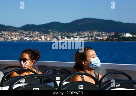 12th July 2020, Ria de Vigo, Galicia, northern Spain: Passengers wearing face masks on the ferry from Vigo to the Cies Islands, a popular tourist destination off the coast of Galicia. Spain has relaxed travel restrictions from 21st June after a strict lockdown to control the Covid 19 coronavirus and many Spaniards are returning to the beaches. Wearing face masks is still mandatory on public transport. Stock Photo