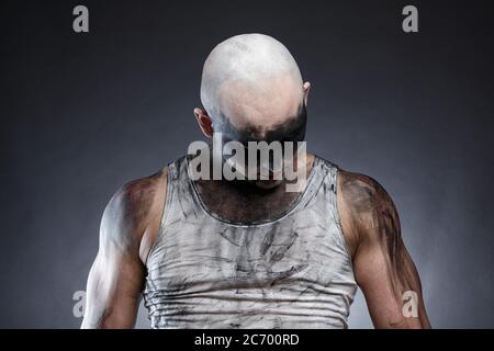 Photo of bald dirty man with head down on gray background Stock Photo