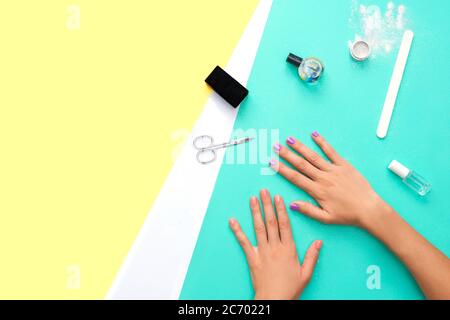 Beautifully manicured orange and violet nails on the mint background with tools for manicure. Flat lay. Place for text on yellow background. Stock Photo