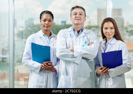 Portrait of positive confident doctors in white labcoats standing in clinic and smiling at camera Stock Photo