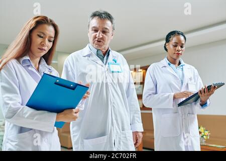 Mature experinced doctor helping intern with making diagnosis after she took anamnesis Stock Photo