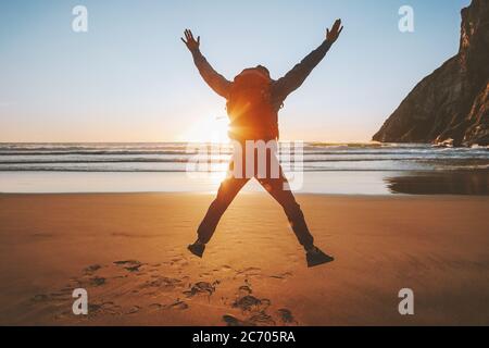 Man jumping on beach travel healthy lifestyle active vacations outdoor adventure success happy emotions traveler enjoying sunset ocean landscape Stock Photo