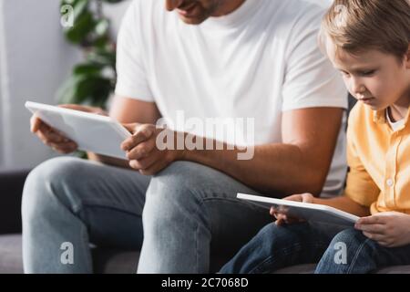 cropped view of father and adorable son using digital tablets at home Stock Photo