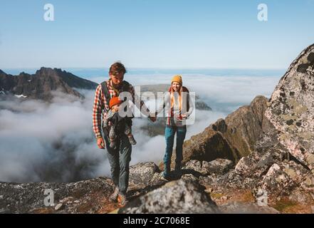 Family travel vacations man and woman hiking with baby carrier outdoor in mountains healthy lifestyle mother and father walking holding hands summer t Stock Photo