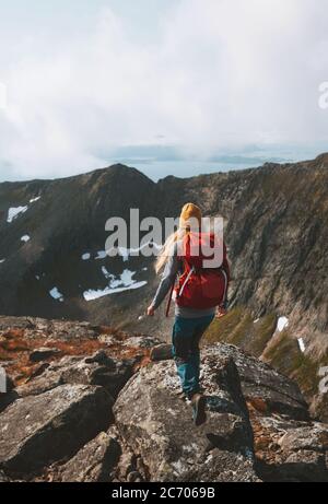 Woman trail running in mountains with red backpack travel lifestyle hiking solo active summer vacations outdoor adventure journey in Norway Stock Photo