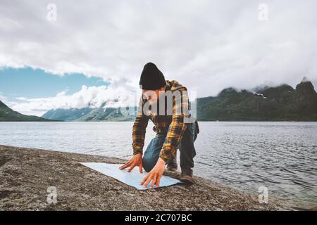 Man looking at map planning vacation route trip traveling solo in Norway active adventure lifestyle wilderness survival sea fjord and foggy mountains Stock Photo